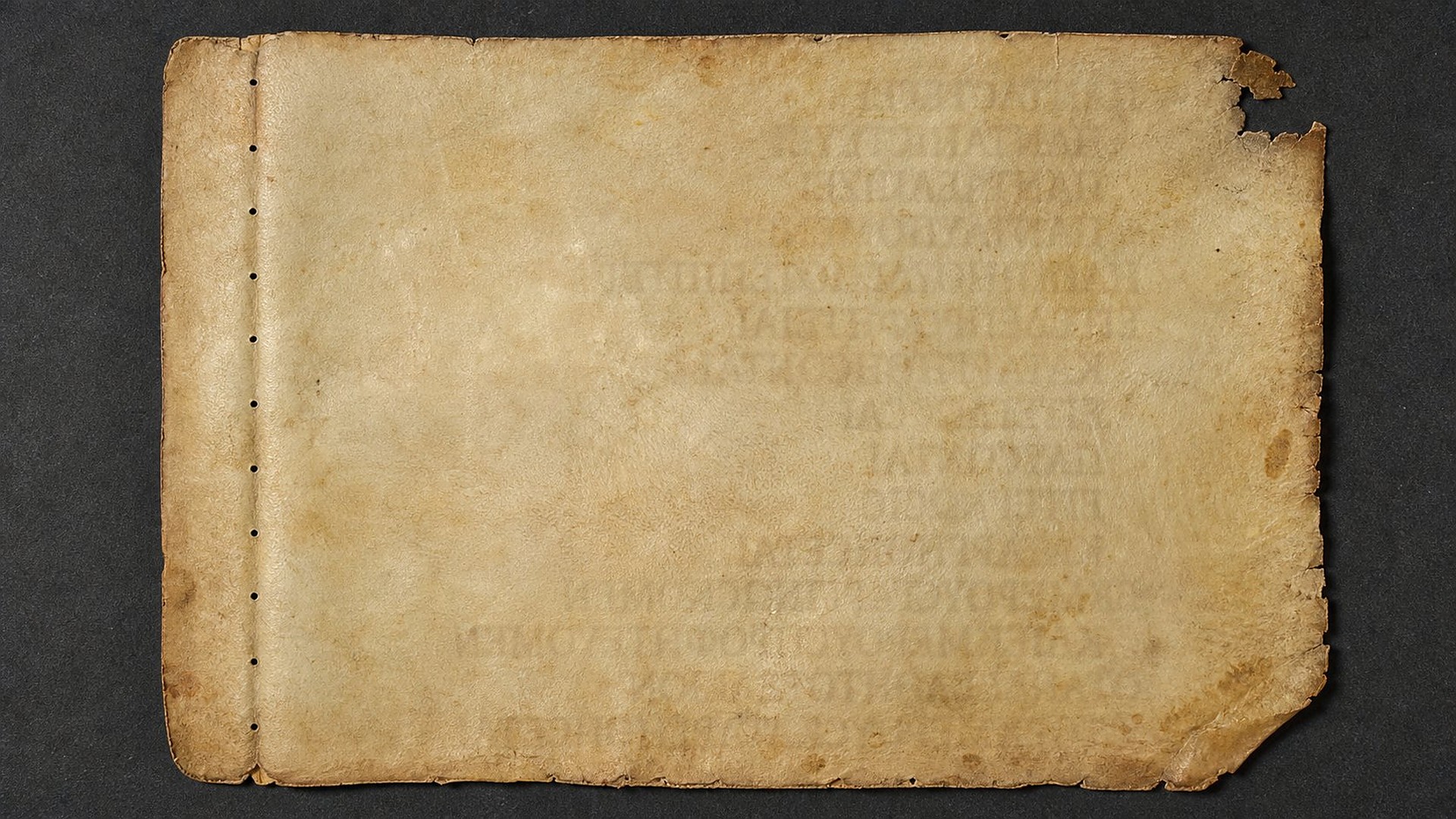 Feuillet de parchemin jauni, troué par une ancienne couture ; on devine à peine des traces d'écriture