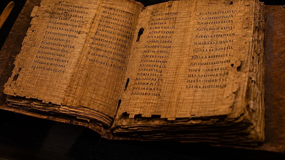Un codex de papyrus du IVe siècle ouvert dans une vitrine, avec ses colonnes d'écriture copte